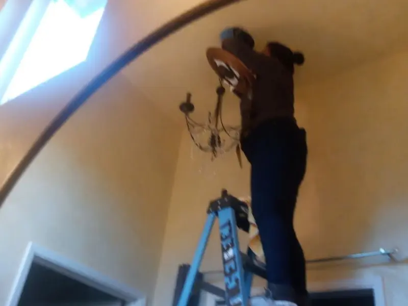 Electrician installing a chandelier in a Dimmitt residence